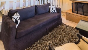 A cozy living room with a dark sofa, a chandelier, and a fireplace. - Ilaeira Mountain Resort (Sparta)