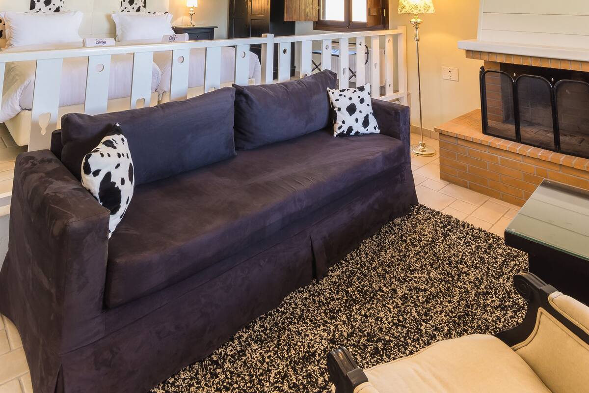 Ein gemütliches Wohnzimmer mit einem dunklen Sofa, einer Chandelüster und einem Kamin.