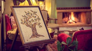 Una obra de arte en mosaico con forma de árbol, enmarco, sobre un caballete en un salón acogedor con chimenea al fondo.