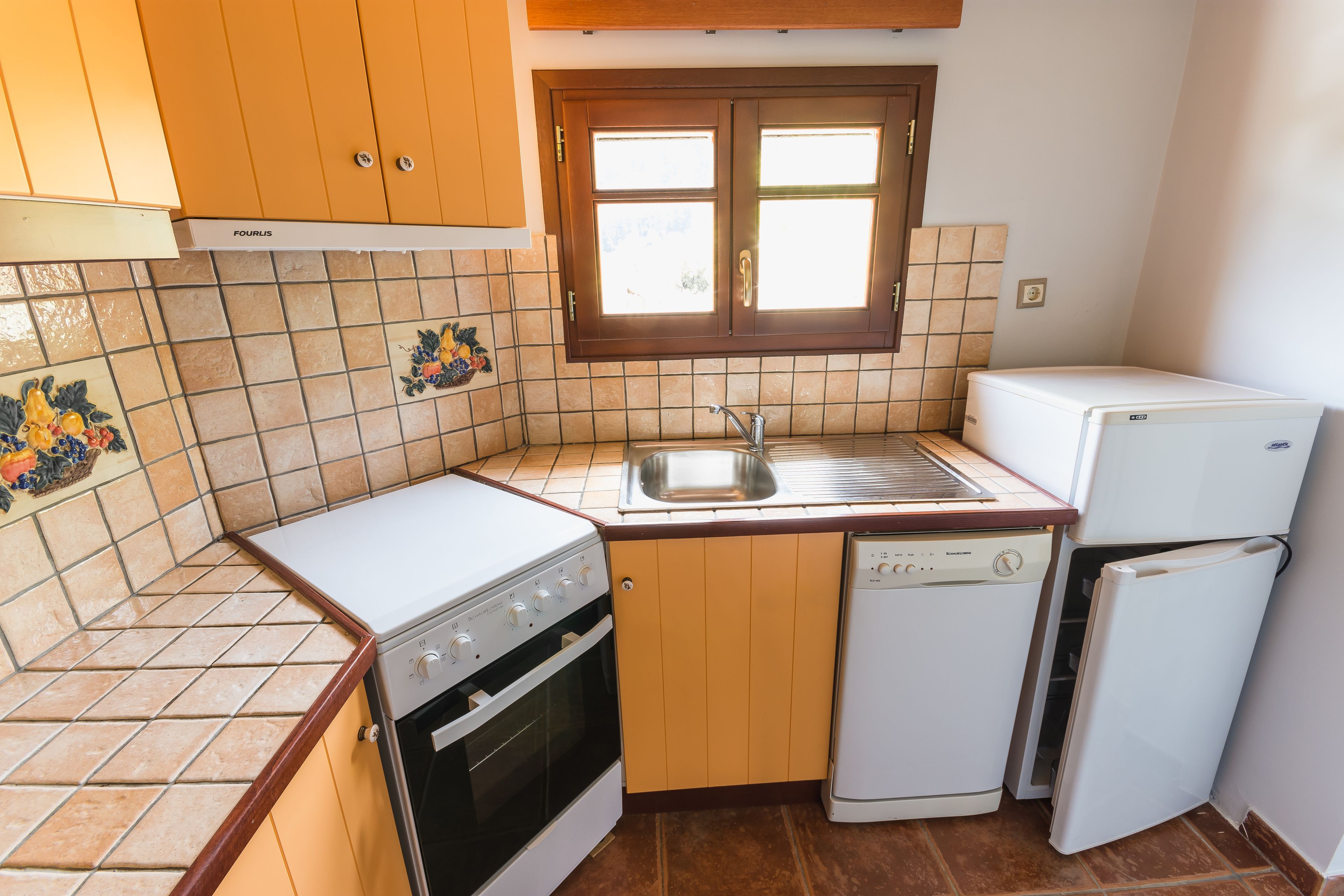 A compact kitchen with a stove, oven, dishwasher, and refrigerator.