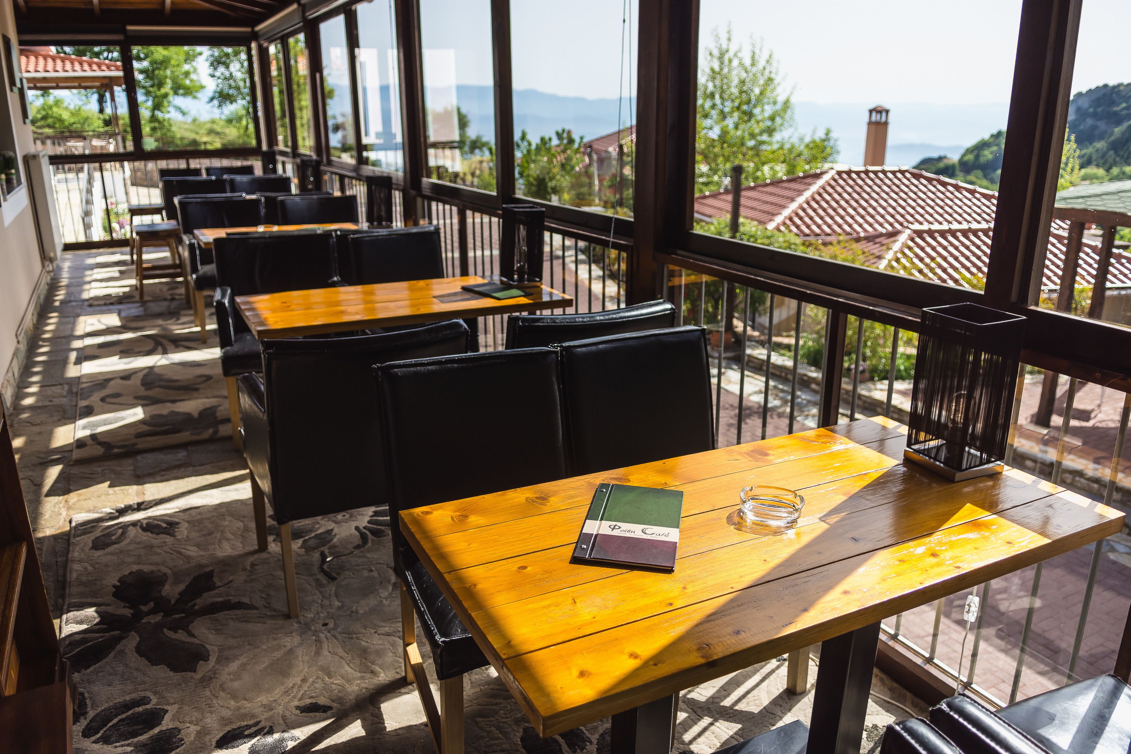 Ein Restaurant mit Außenbereich, Holztischen und schwarzen Stühlen.