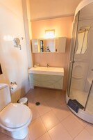 Uma casa de banho moderna com sanita, lavatório e cabine de duche em vidro.