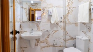 A bathroom with a marble backsplash, a sink, a toilet, and a mirror. - Hotel Color (Varna)