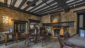 A rustic pub interior with exposed beams, stone walls, wooden furniture, and a fireplace. - The White Hart Royal Hotel, Moreton-in-Marsh (Moreton-in-Marsh)