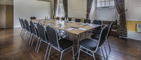 A conference room with a long table, chairs, and a projector screen.