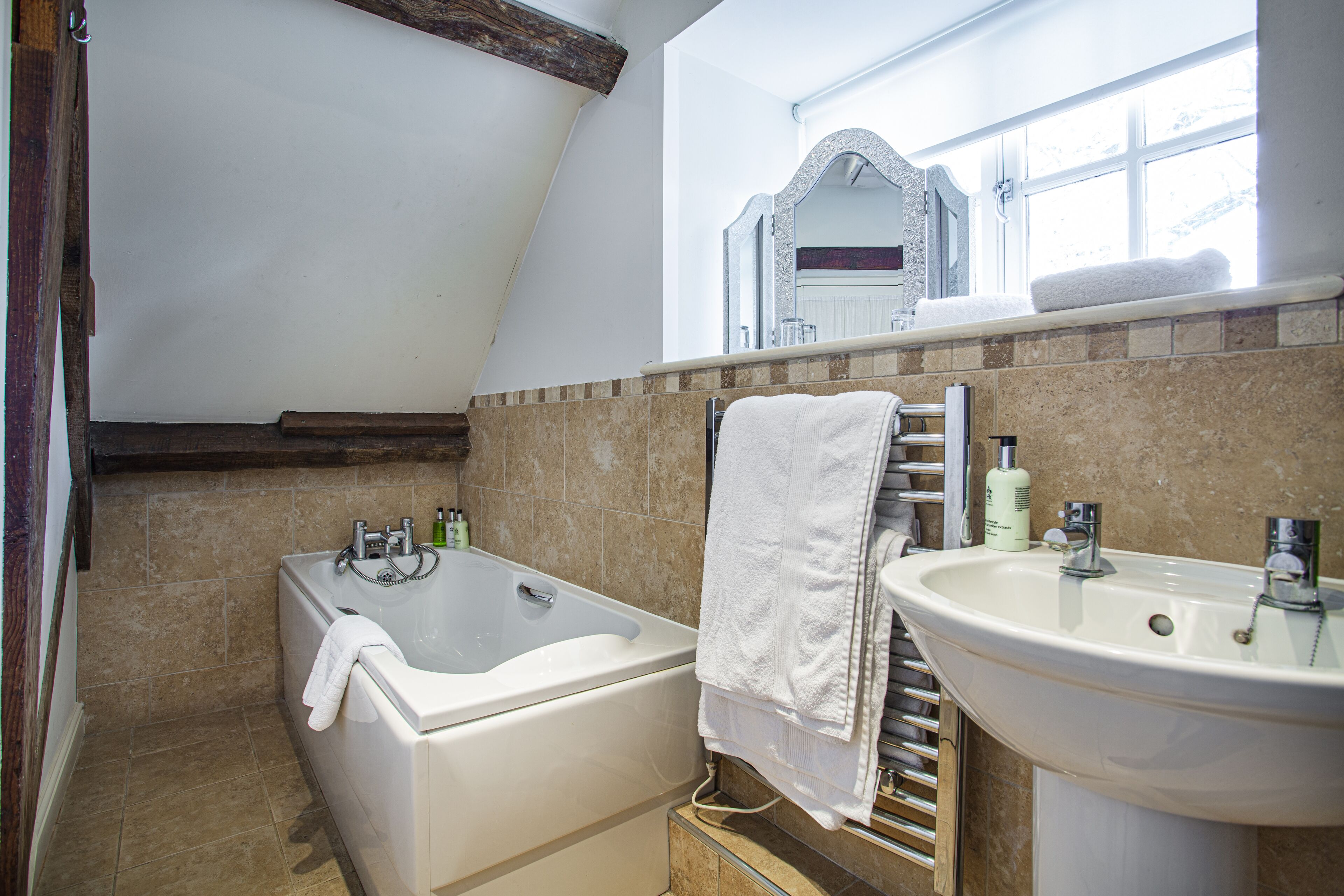 A bathroom with a bathtub, a sink, and a window.