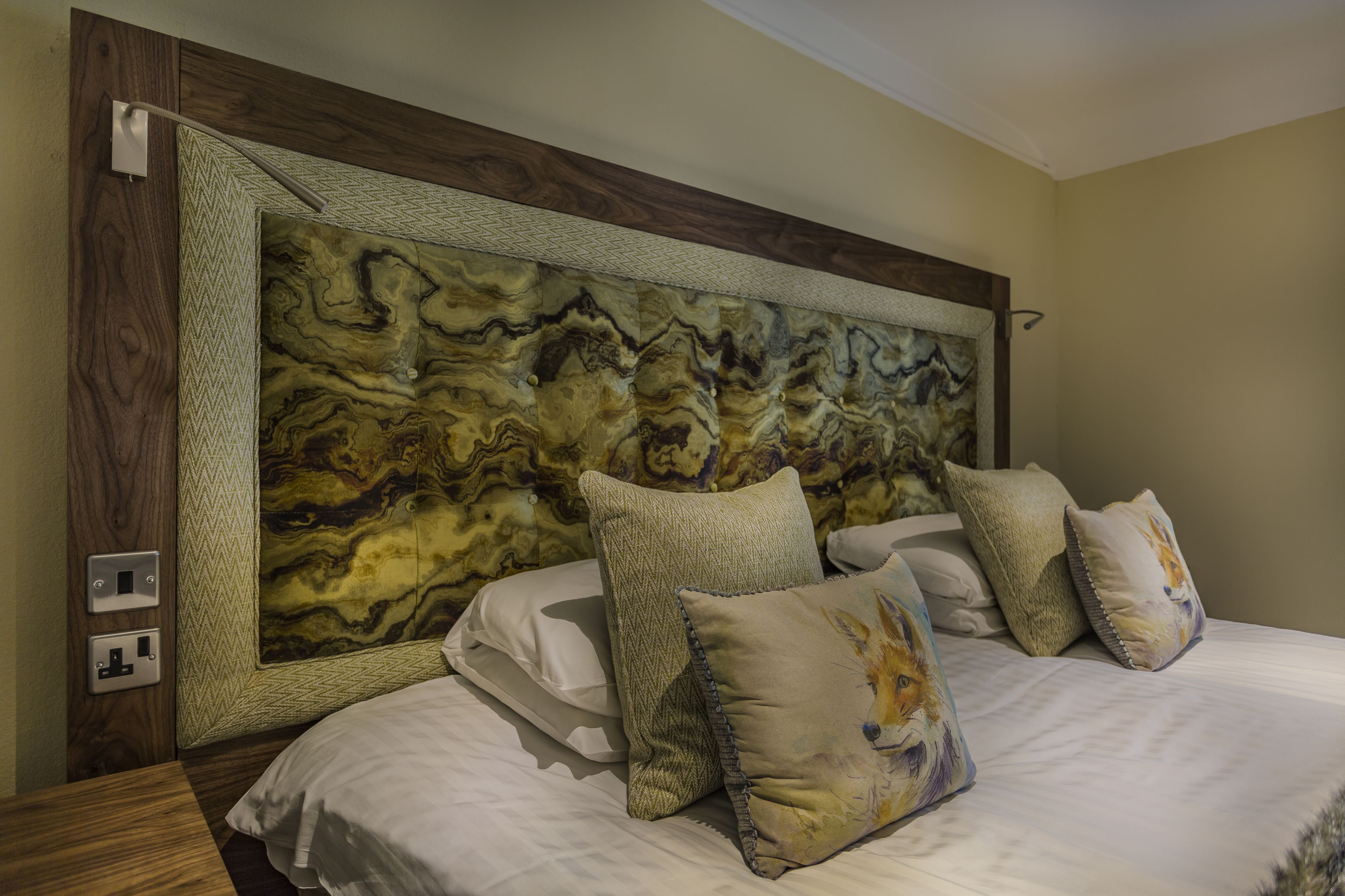 Un dormitorio con una cama grande, varias almohadas, un cabecero de madera y un panel de pared texturizado.