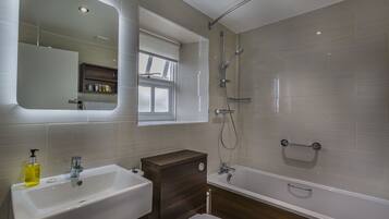 A modern bathroom with a sink, toilet, and bathtub.
