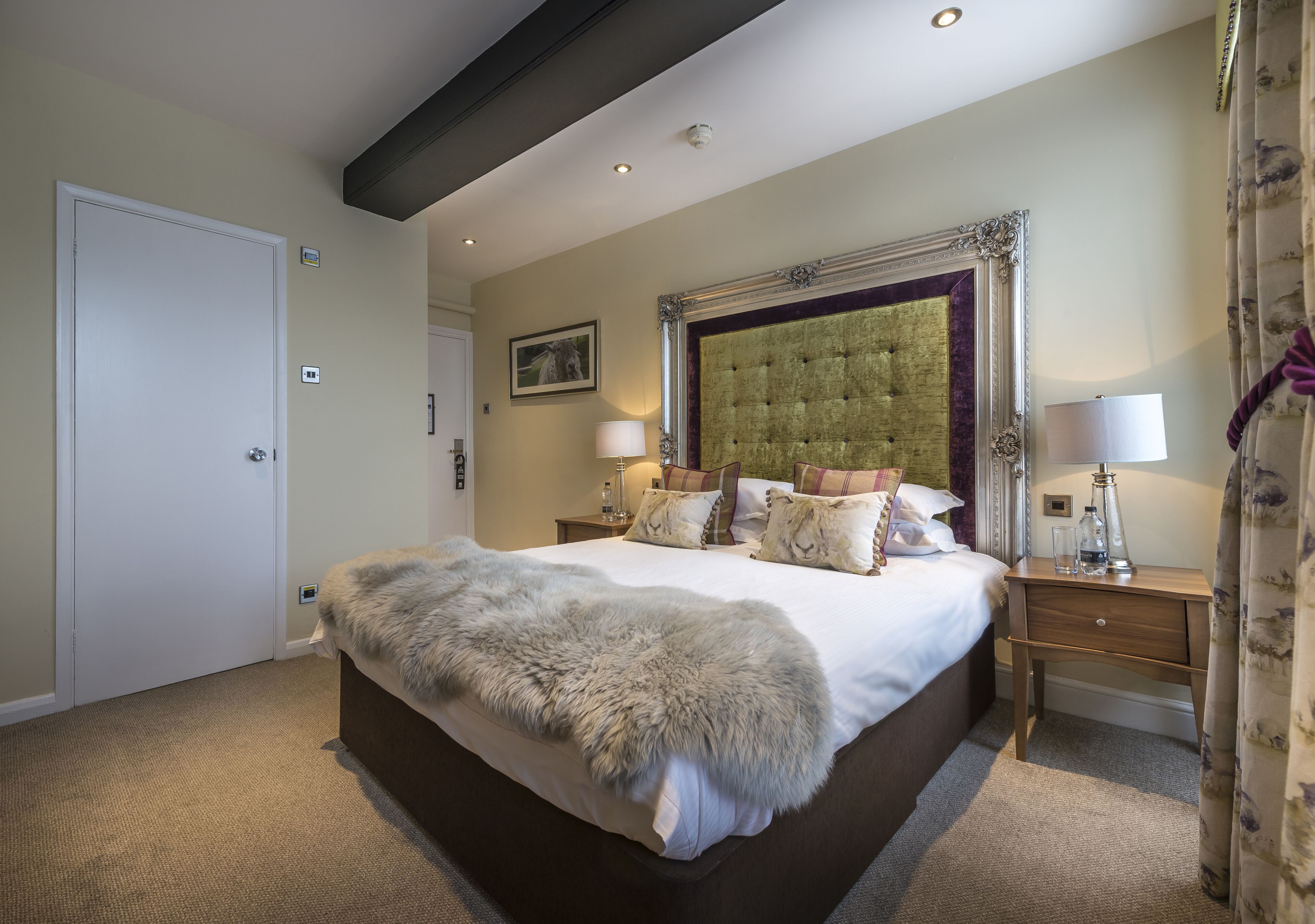 A bedroom with a large bed, a headboard, two bedside tables, and a door.