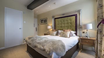 A bedroom with a large bed, a headboard, two bedside tables, and a door.