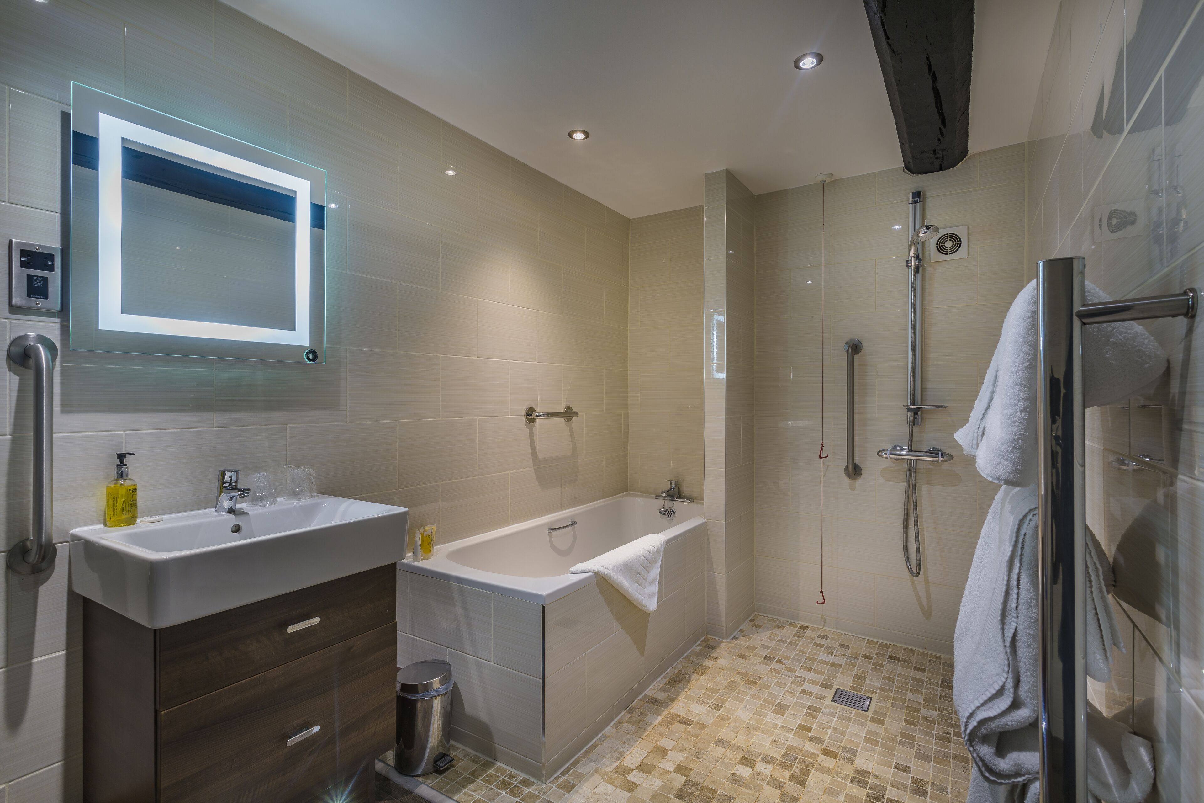A modern bathroom with a sink, vanity, bathtub, and shower.