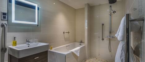 A modern bathroom with a sink, vanity, bathtub, and shower.