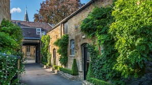 A narrow street with stone buildings, one with ivy-covered walls and a traditional design. - The White Hart Royal Hotel, Moreton-in-Marsh (Moreton-in-Marsh)