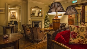 A cozy hotel lobby with a fireplace, a Christmas tree, and classic furniture. - The White Hart Royal Hotel, Moreton-in-Marsh (Moreton-in-Marsh)