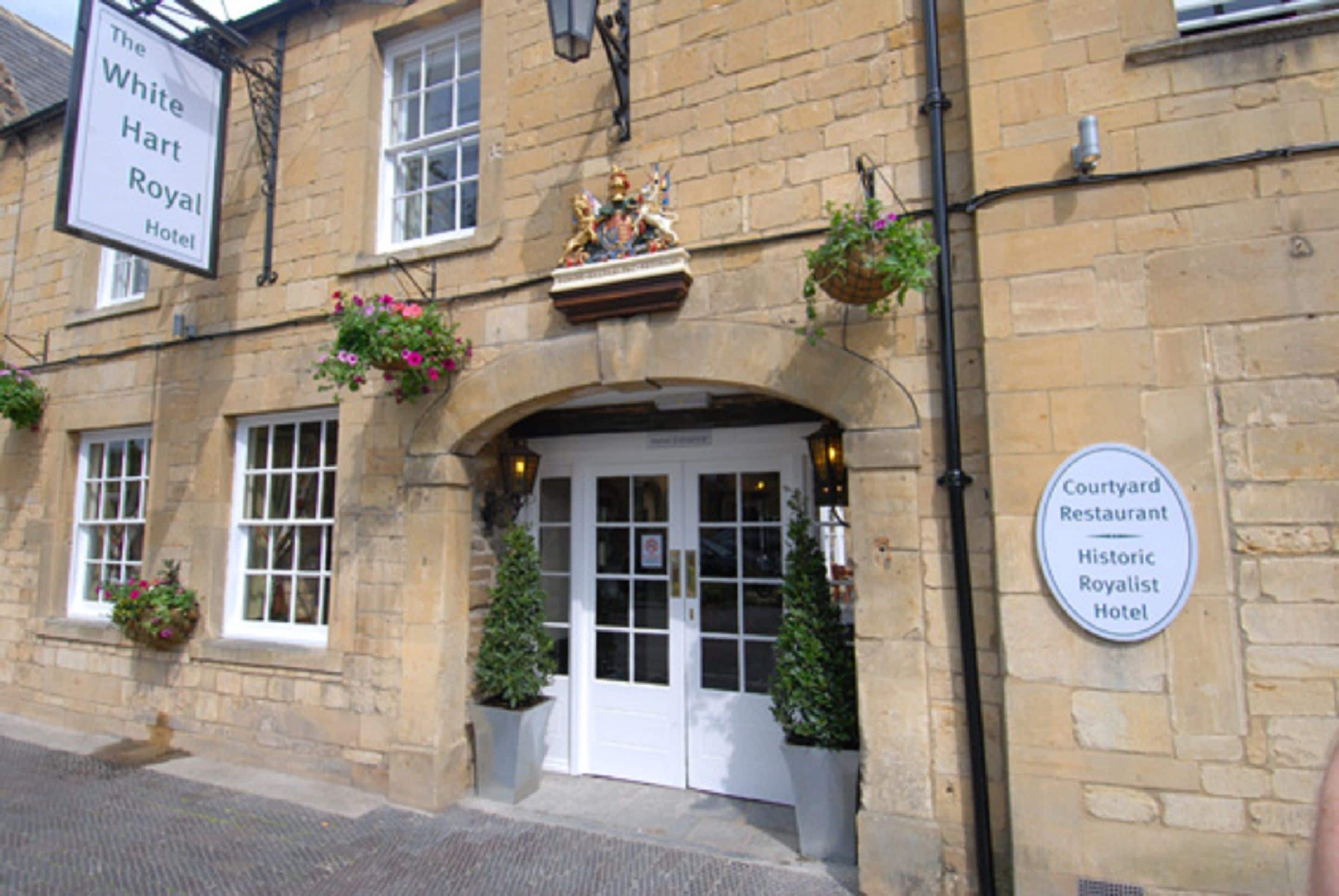 Un bâtiment historique portant une enseigne indiquant « The White Hart Royal Hotel » et « Courtyard Restaurant ».