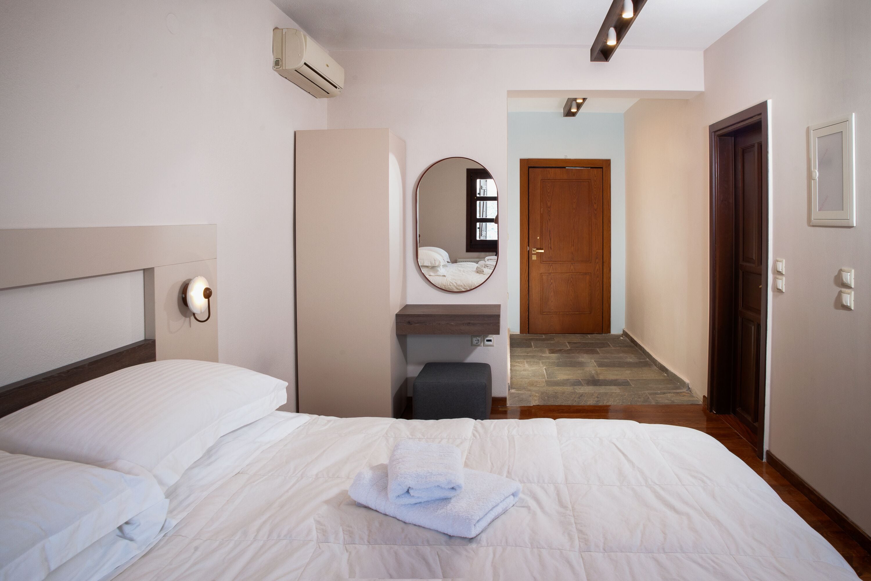 Ein Hotelzimmer mit einem Bett, einem Nachttisch, einem Spiegel und einer Tür zu einem anderen Raum.