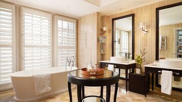 A modern bathroom with a freestanding bathtub, a round glass table, and a large mirror.