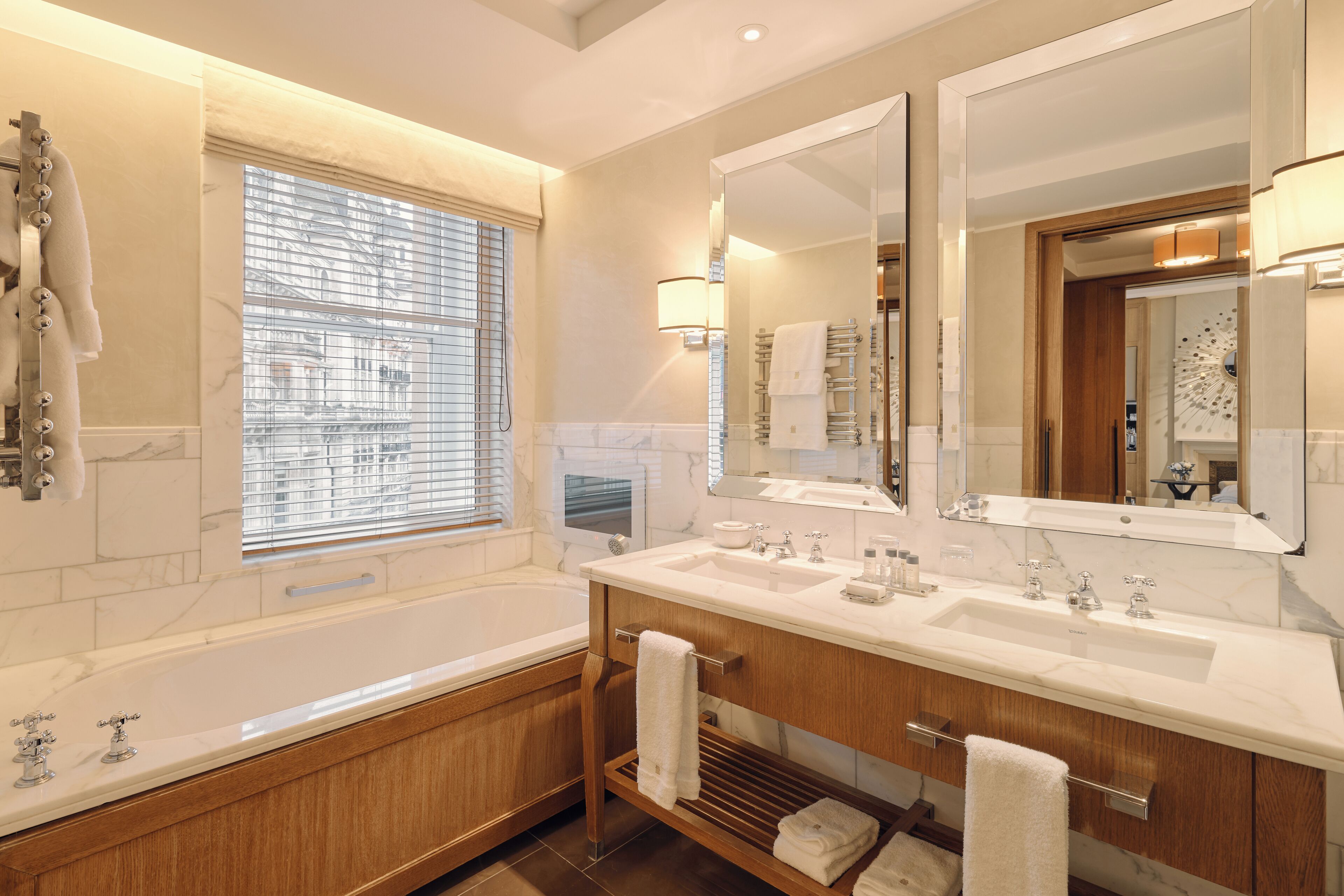 A modern bathroom with a large bathtub, double sinks, and a large mirror.