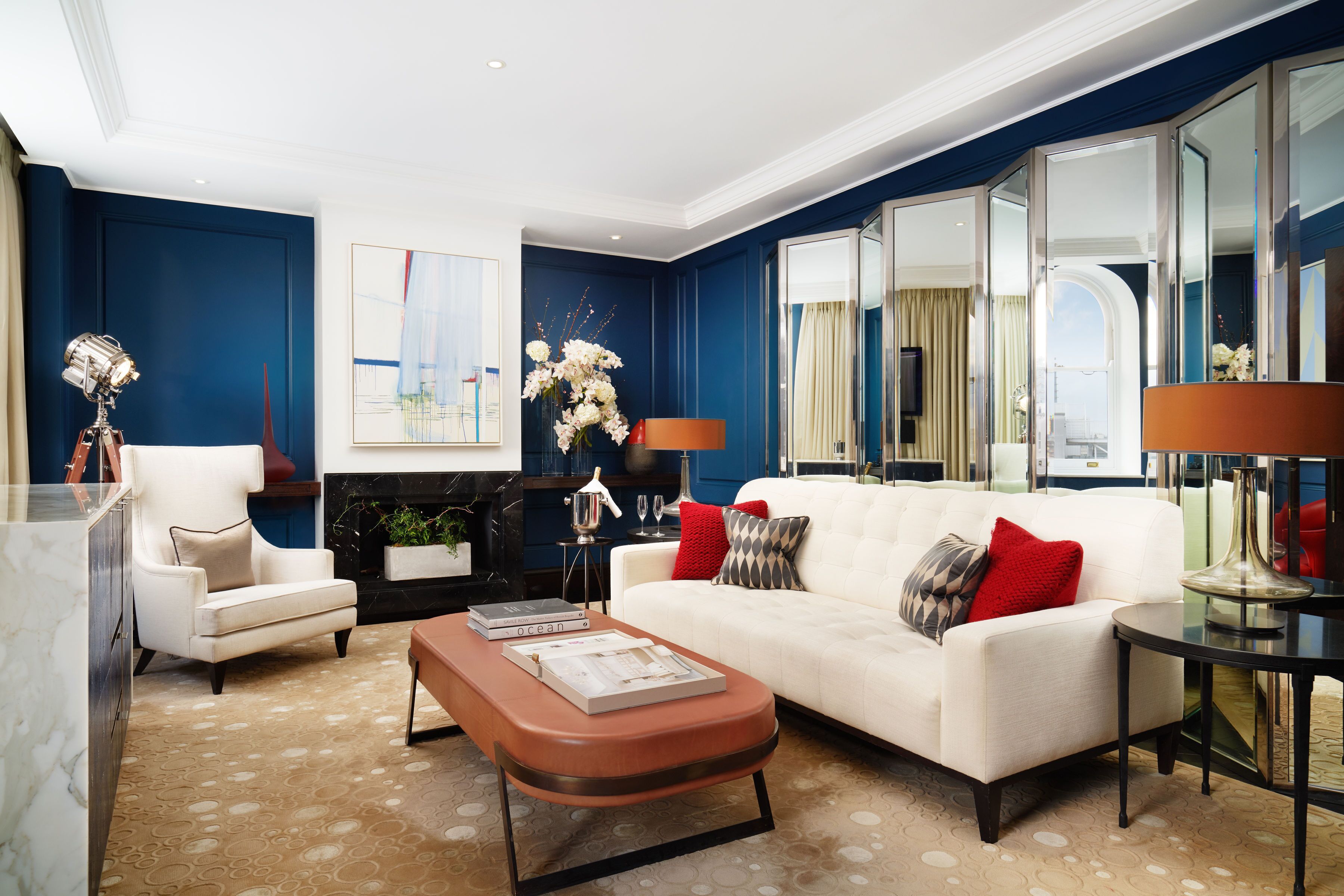 A modern living room with a white sofa, red and grey pillows, a coffee table, and a fireplace.
