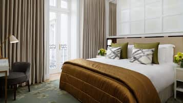 Een hotelkamer met een groot bed, een bureau met lamp en uitzicht naar buiten door een groot raam.