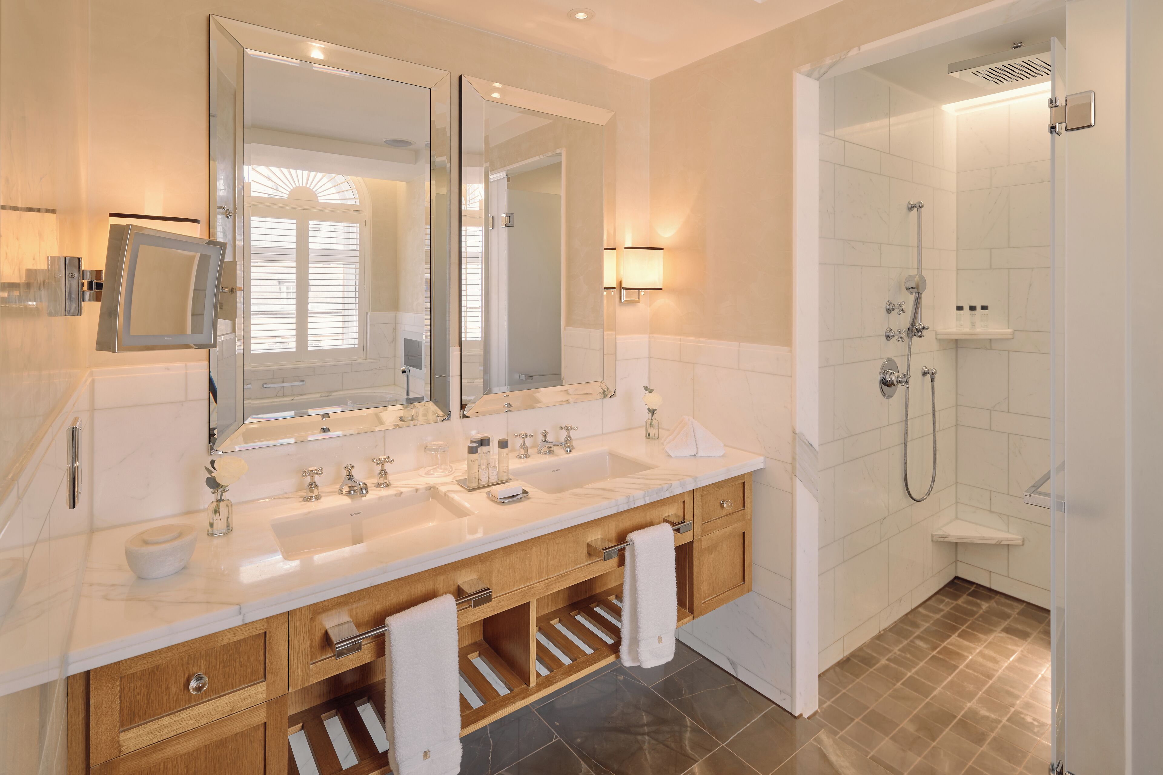 A modern bathroom with a double sink vanity, a large mirror, and a walk-in shower.