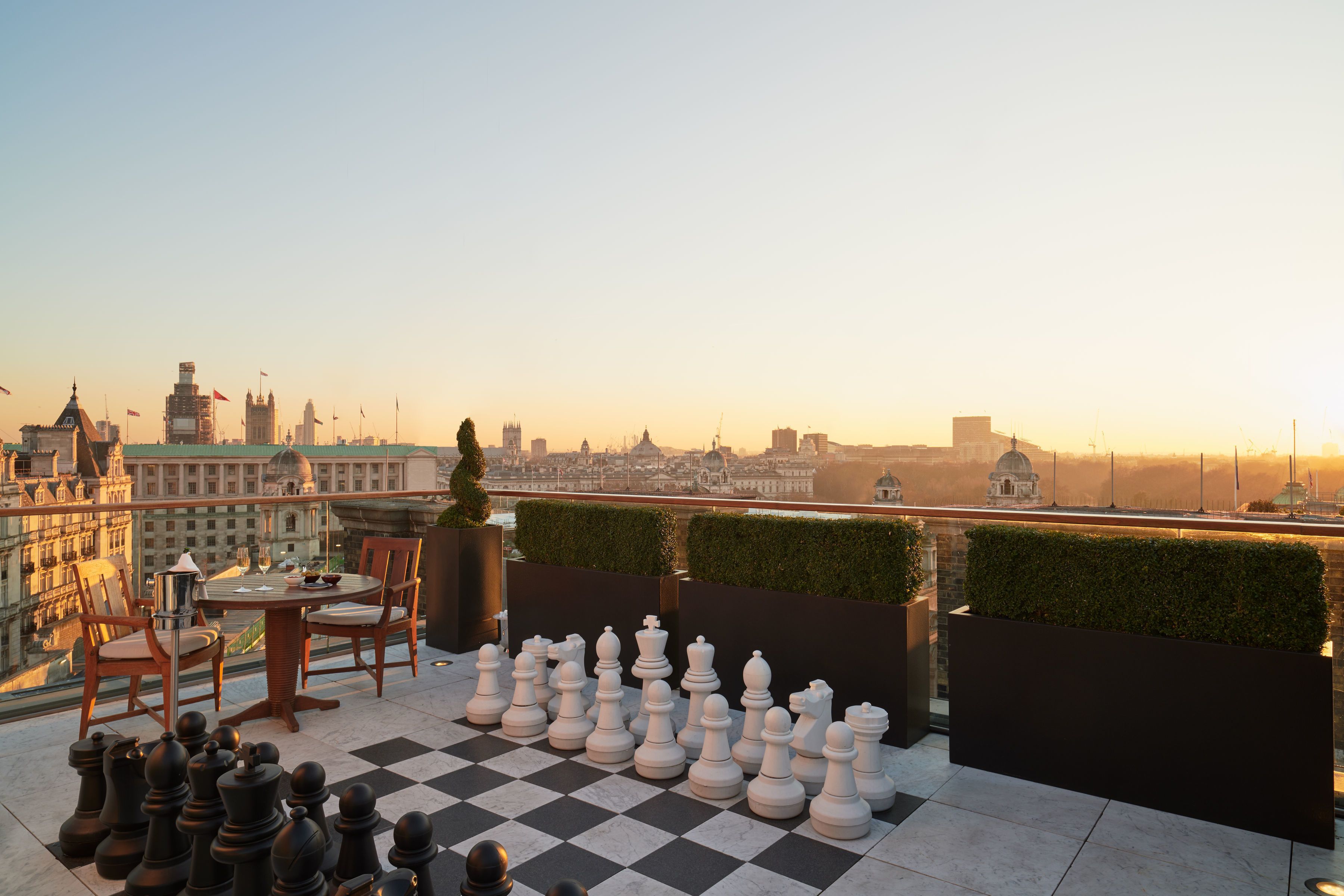 Una scacchiera con pedine su una terrazza sul tetto con vista sulla città.