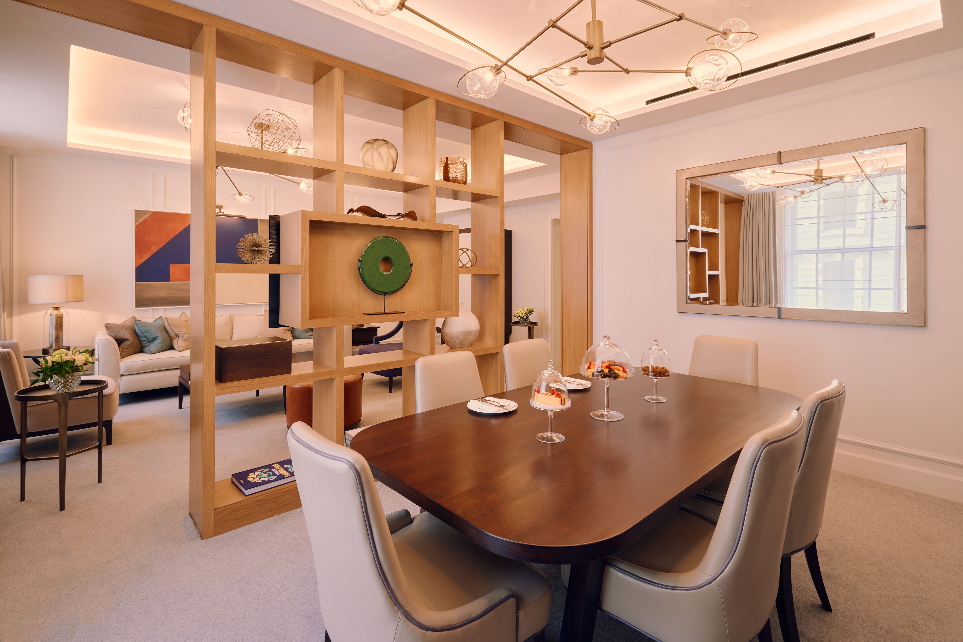 A modern dining area with a wooden partition, a large mirror, and a dining table set for four.