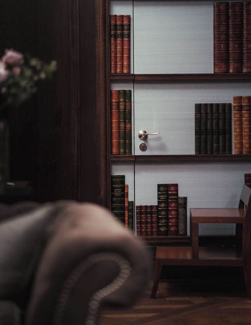Ein Bücherregal mit Büchern, ein Holzstuhl und eine Tür.