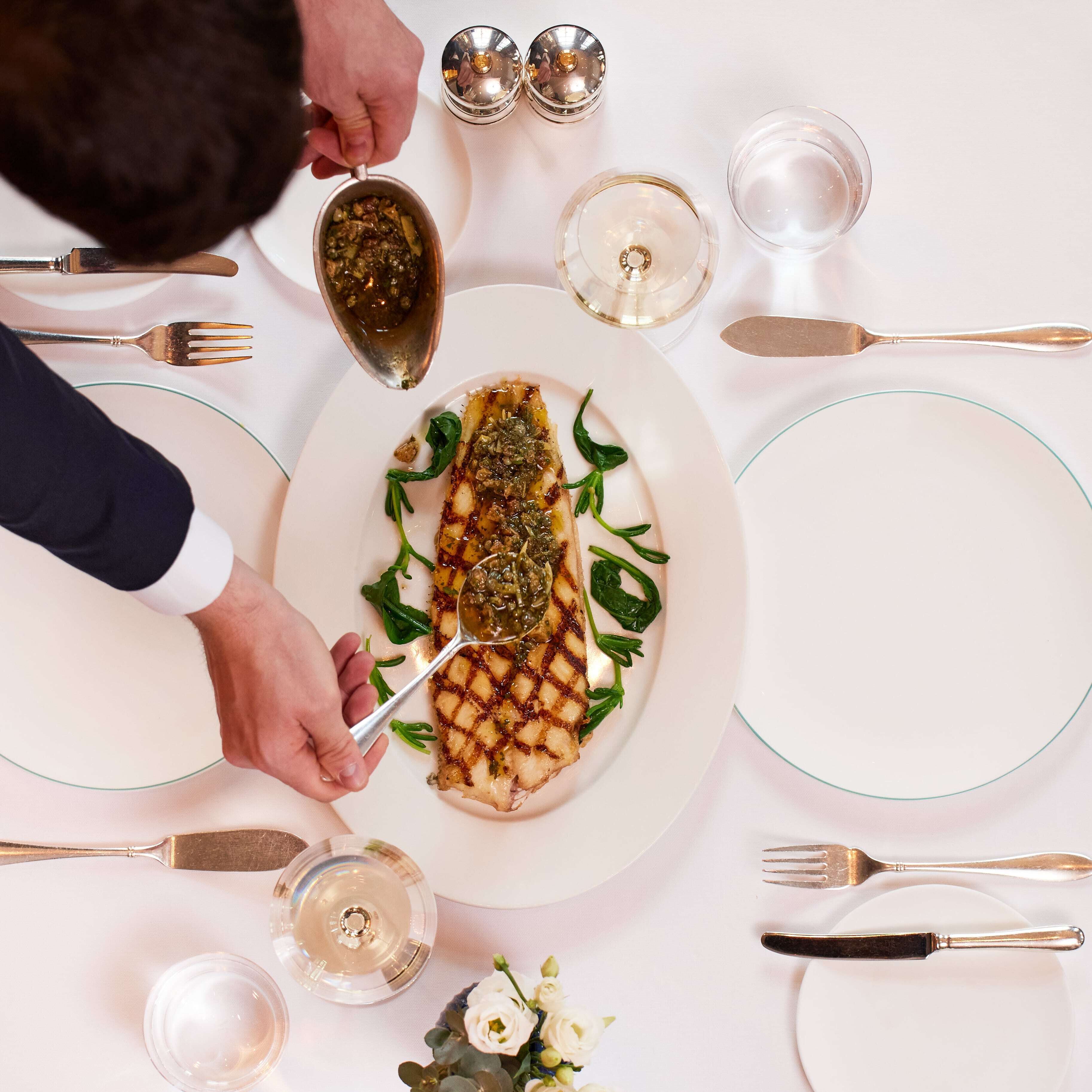 Una mesa de comedor dispuesta con platos, cubiertos y un vaso de agua.