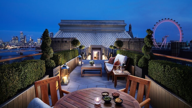 A rooftop terrace with a view of the city skyline, including a Ferris wheel, and furnished with outdoor seating and tables. - Corinthia London (London)
