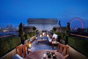 A rooftop terrace with a view of the city skyline, including a Ferris wheel, and furnished with outdoor seating and tables. - Corinthia London (London)