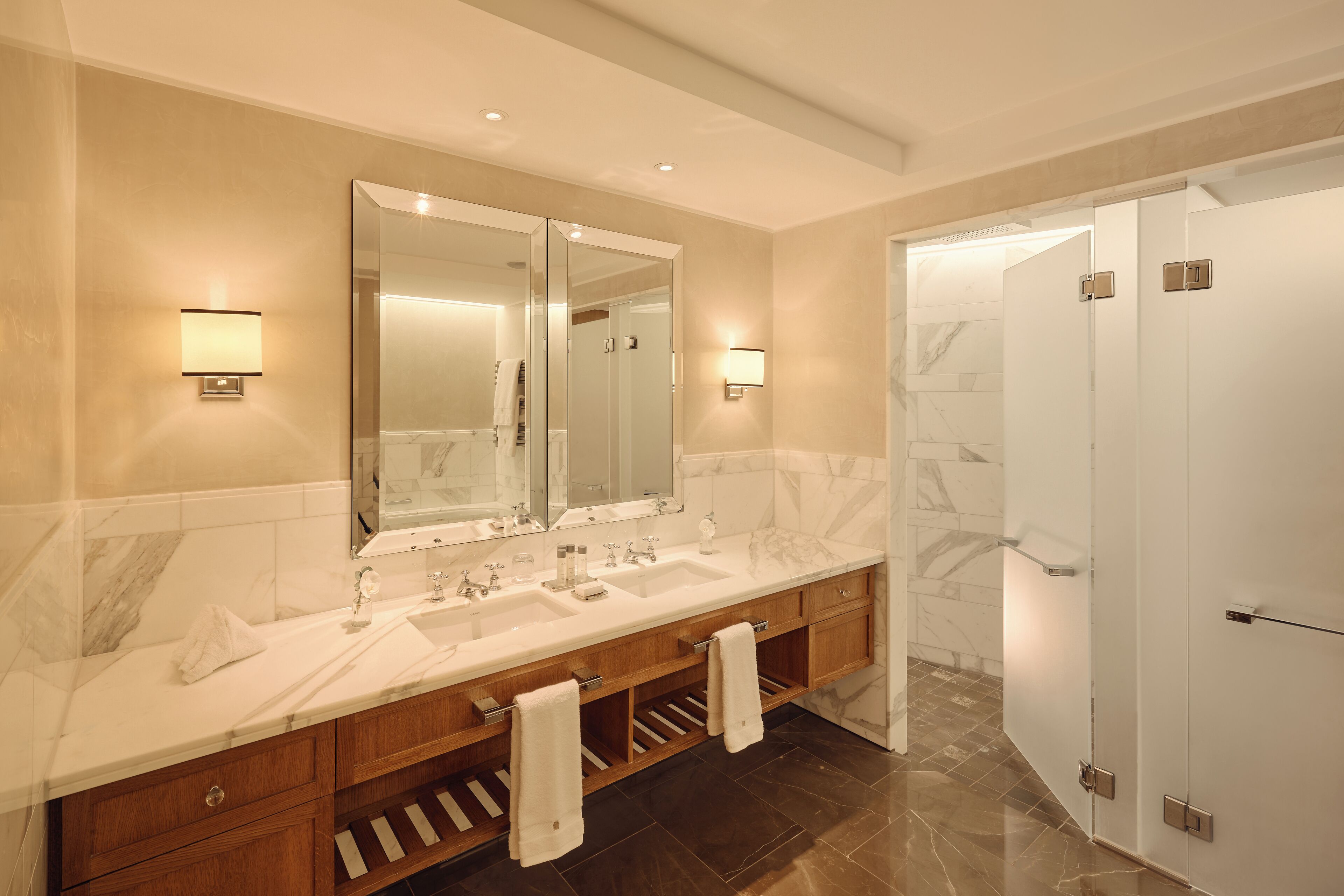 Ein modernes Badezimmer mit einem Doppelwaschbecken, einem großen Spiegel und einer begehbaren Dusche.