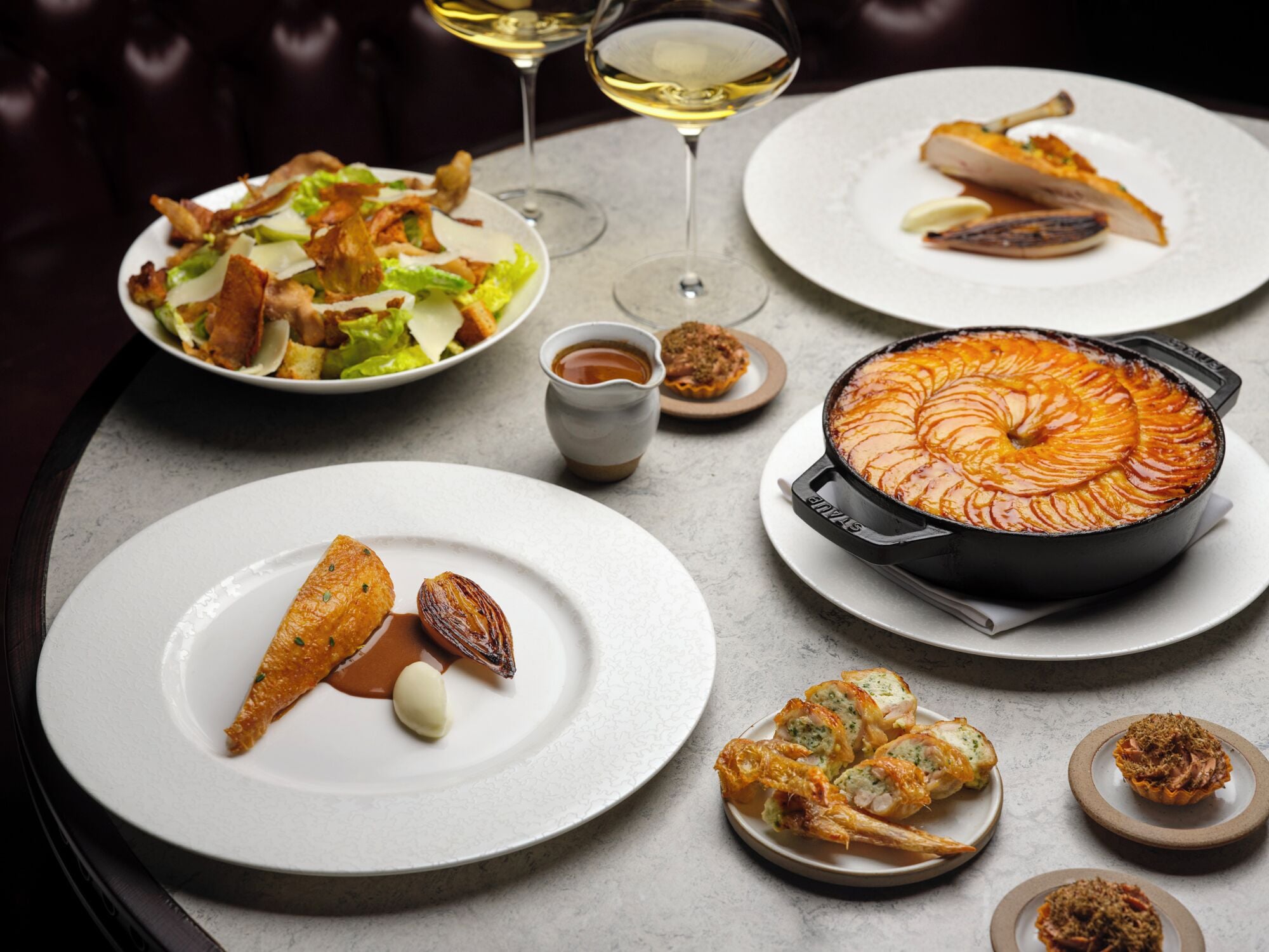 A dining table with various dishes, including a baked tart, seafood, and a salad.