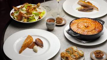 Una mesa de comedor con varios platos, entre ellos una tarta al horno, mariscos y una ensalada.