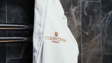 Ein weißes Handtuch mit dem Aufdruck "CORINTHIA LONDON" an einer schwarzen, gefliesten Wand.