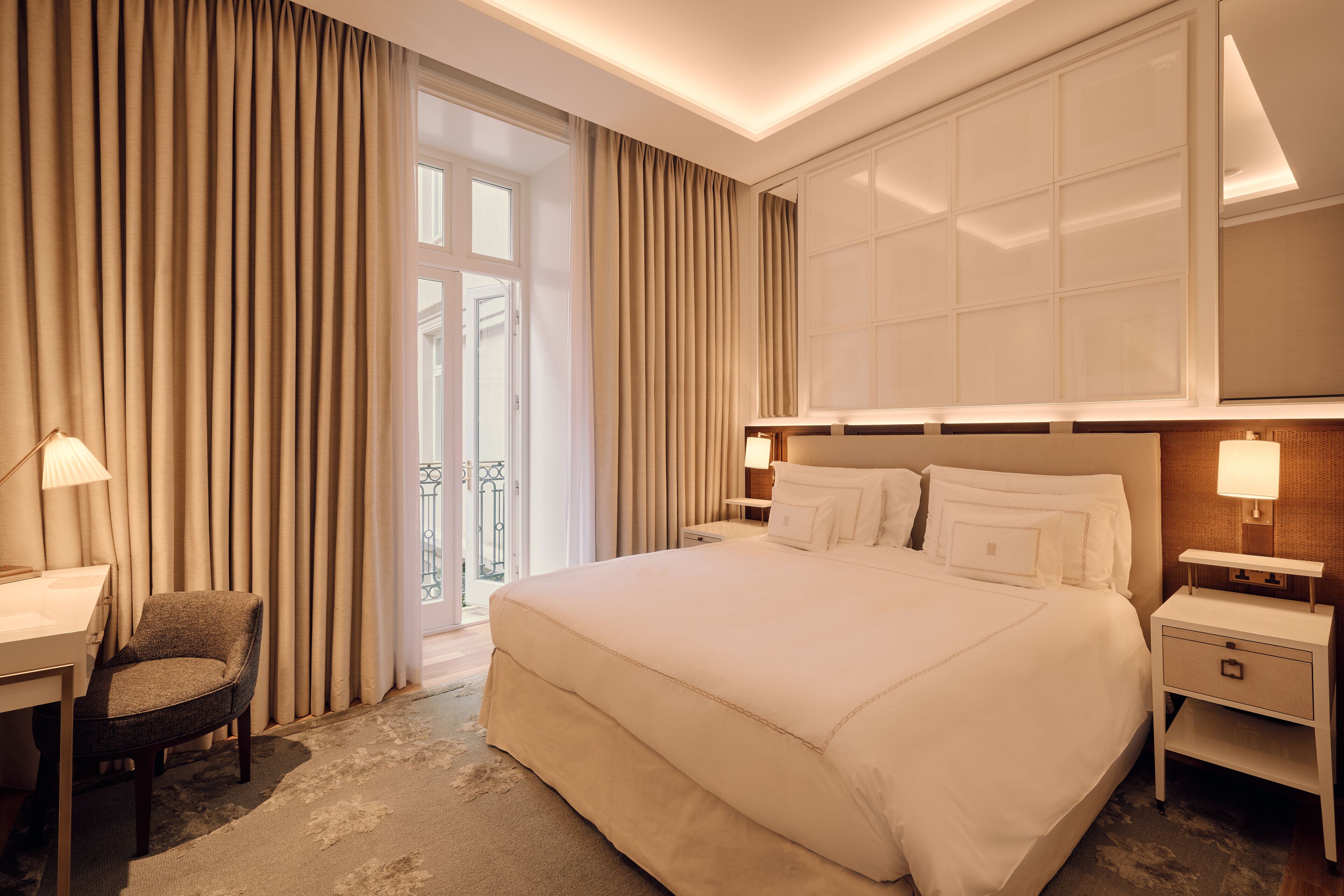 Ein Hotelzimmer mit einem großen Bett, einem Schreibtisch, einem Stuhl und einem Nachttisch mit Lampe.