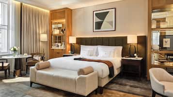 Habitación de hotel con una cama grande, una zona de estar con una silla y una mesa, un escritorio pequeño y una estantería.