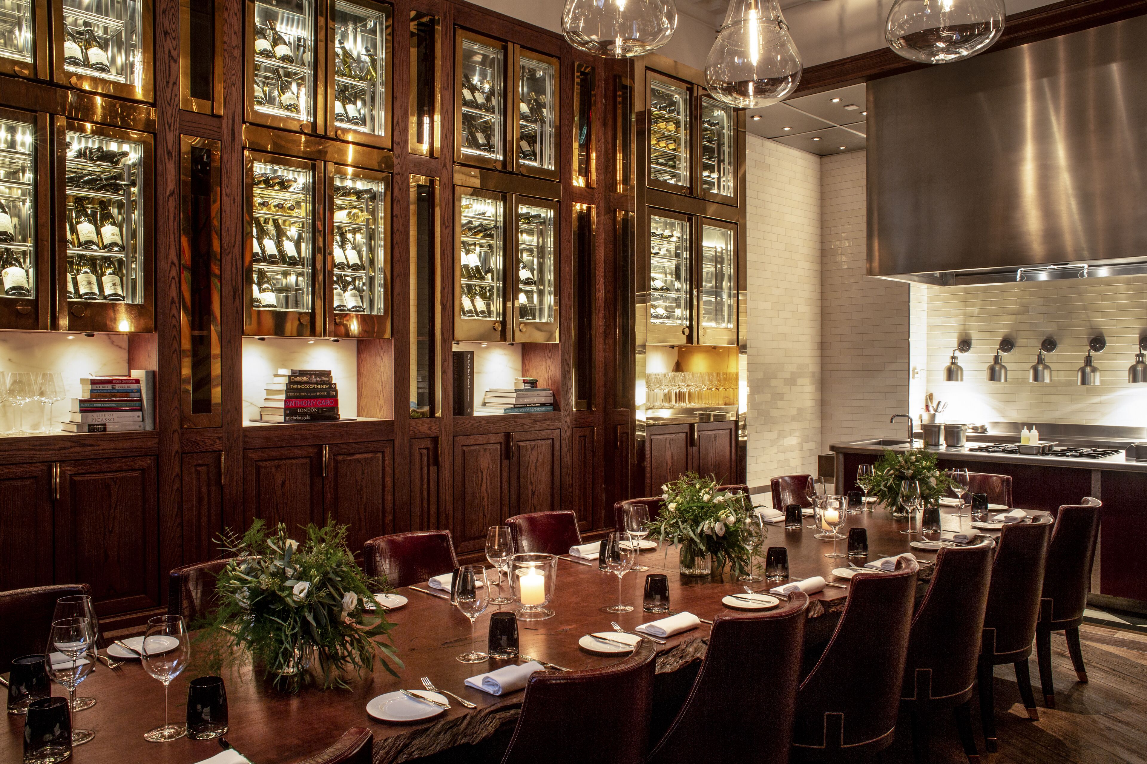 A formal dining area with a long table set for multiple guests, surrounded by wooden paneling and glass display cases.