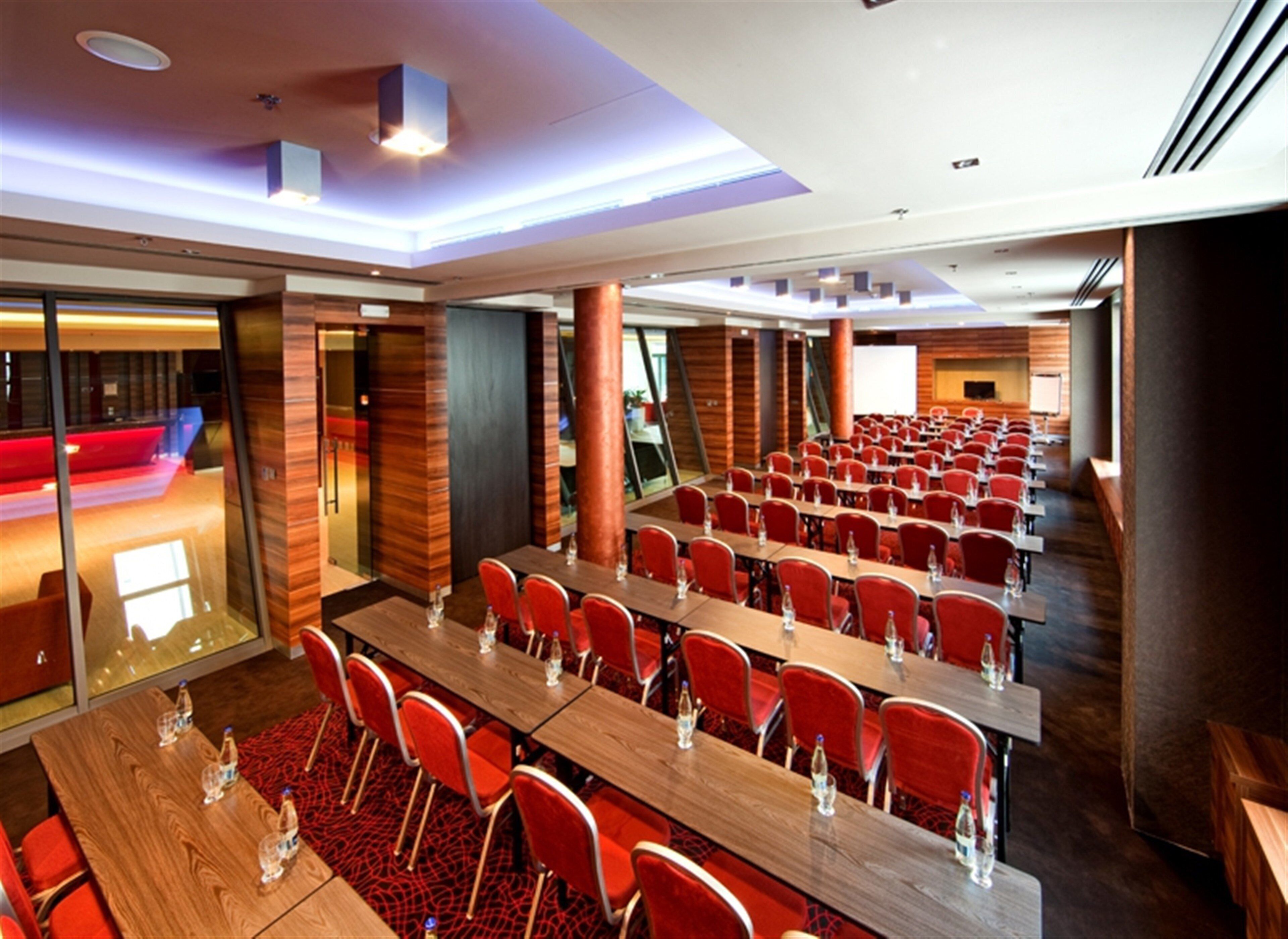 A conference room with multiple tables and chairs, equipped with water bottles, and a red carpet.
