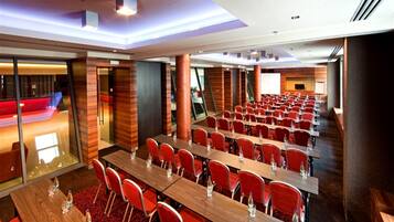 A conference room with multiple tables and chairs, equipped with water bottles, and a red carpet.