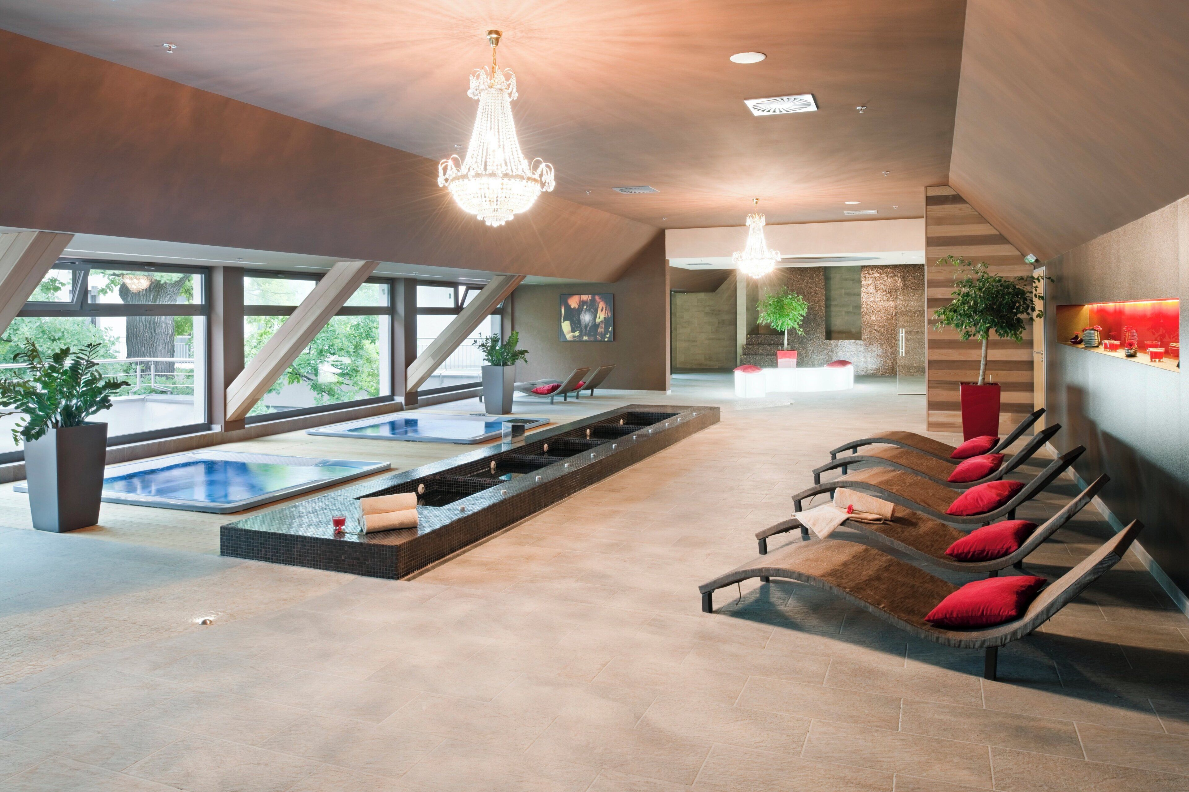 A modern spa area with a large indoor pool, sun loungers, and a reception desk.