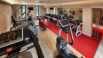A gym with treadmills, elliptical machines, and weight benches.