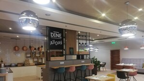 A modern cafe interior with a bar area, seating arrangements, and pendant lighting.