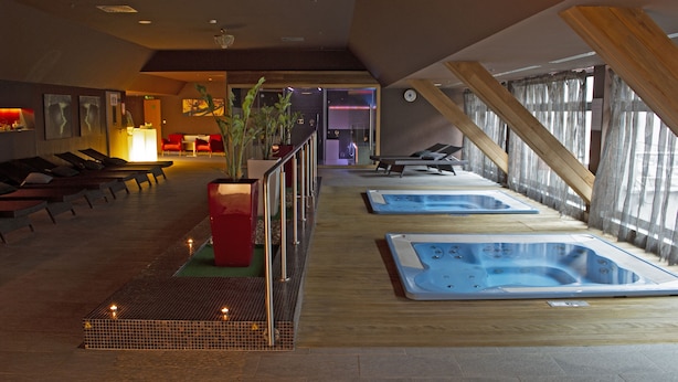 A spa area with multiple hot tubs, a reception desk, and a seating area with chairs and a red planter.