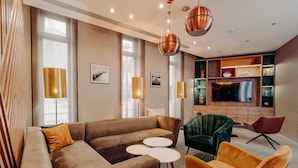 A modern living room with a brown sofa, two white round tables, and colorful chairs.