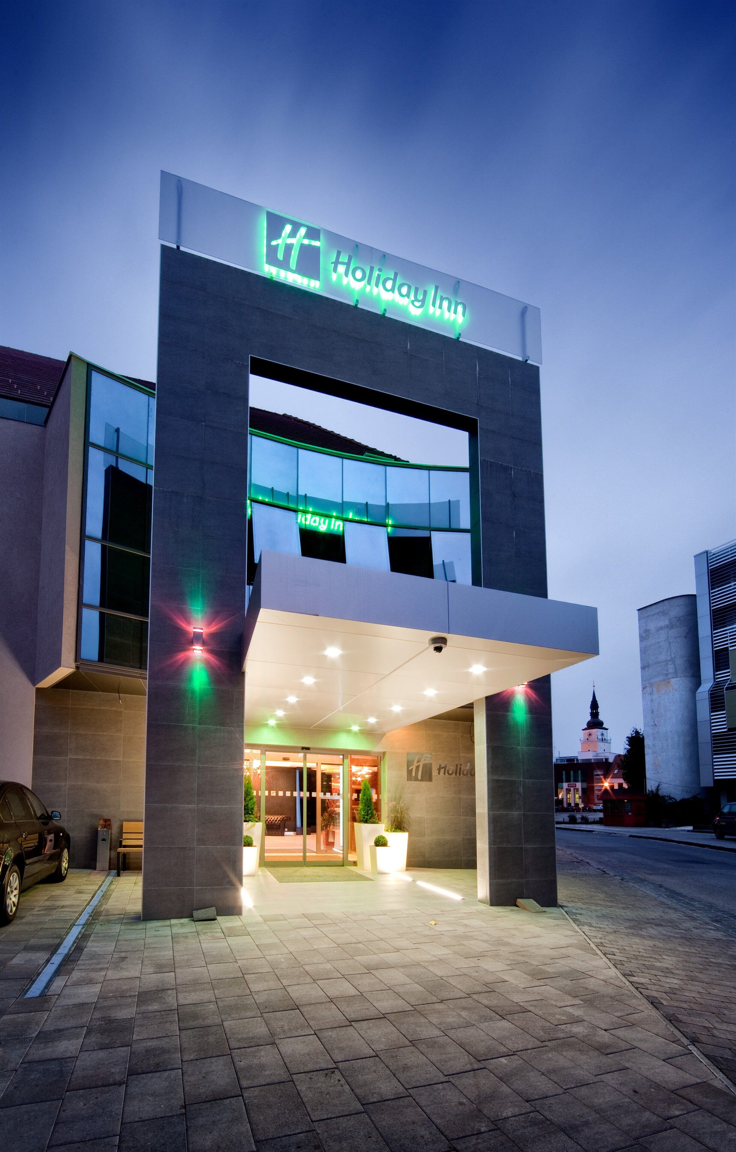 A Holiday Inn hotel entrance with a modern design, featuring a prominent sign and a glass facade.