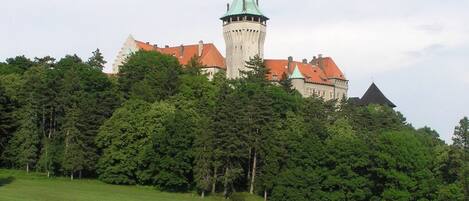 Un castillo con una torre destacada y un edificio de techo rojo.