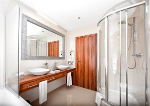 A modern bathroom with a large mirror, two sinks, a wooden vanity, and a glass shower enclosure.
