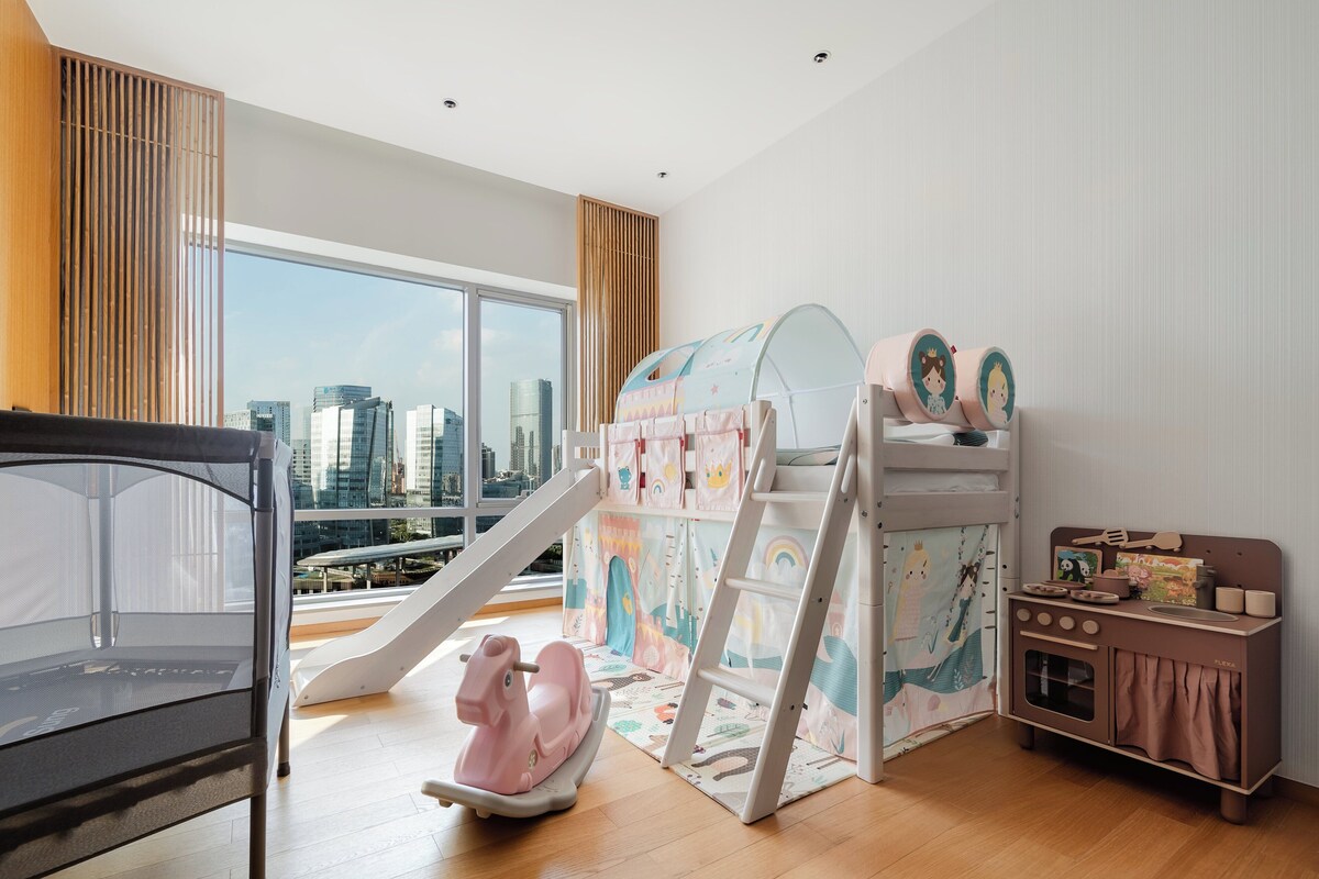 A child-friendly room with a bunk bed, a slide, and a play kitchen.