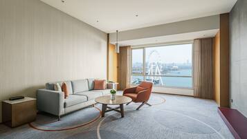 A modern hotel room with a large window offering a view of a city skyline and a Ferris wheel.